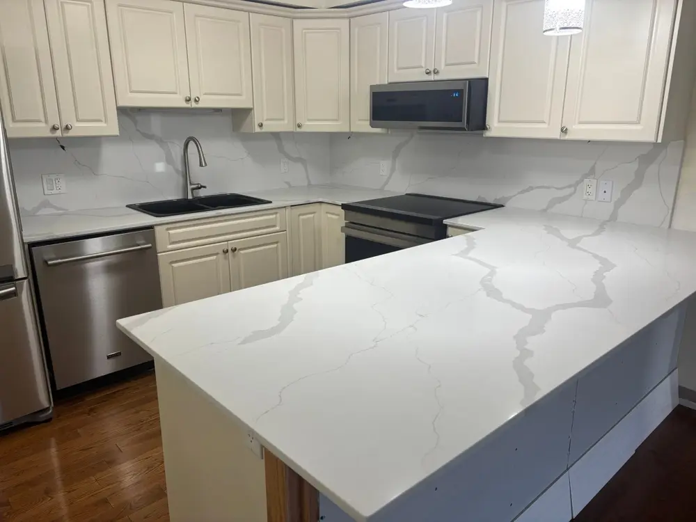 Bold veined peninsula and full-height backsplash with cream cabinets